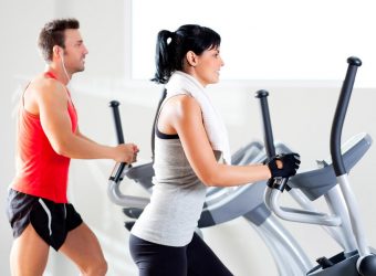 Man and woman with elliptical cross trainer at gym